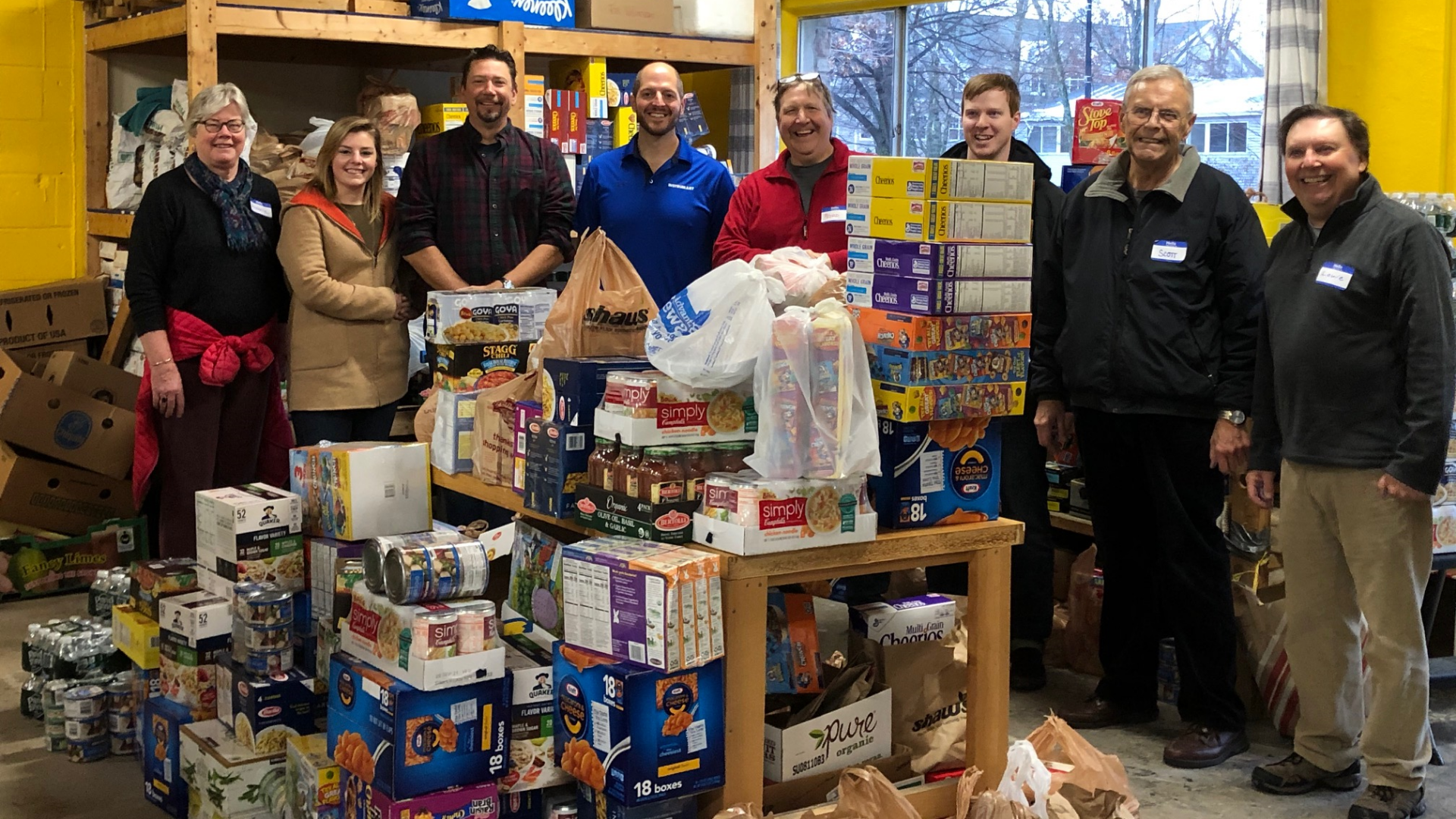 Photo of Instrumart employees posing in front of the 2,238 items of food that were donated during the 2019 holiday season.
