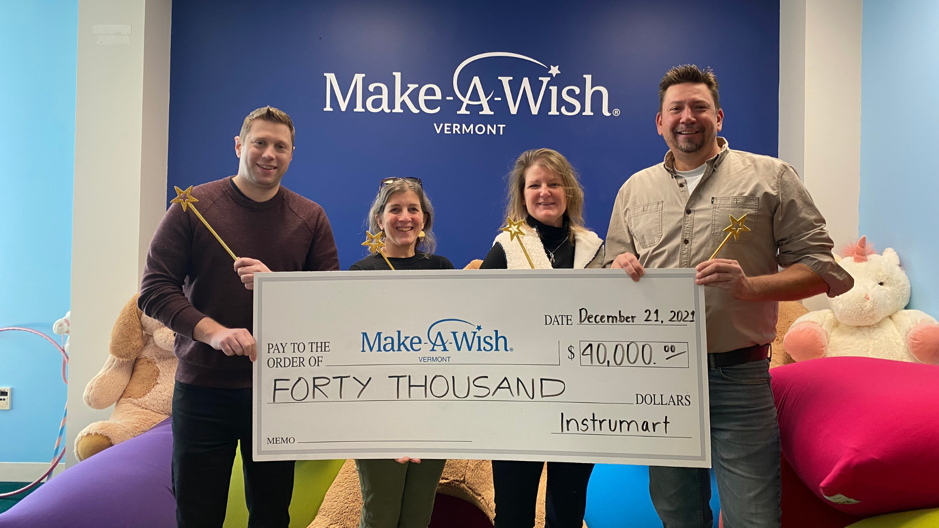 Image of Instrumart employees posing with a check for $40,000 USD that was donated to Make-A-Wish.